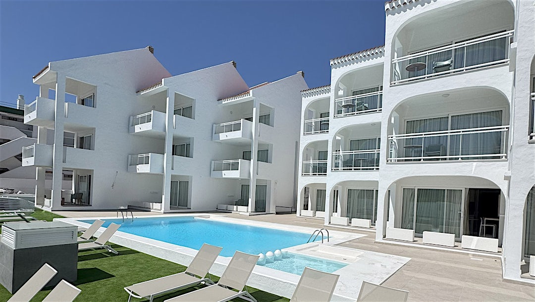 Stilrent poolområde och vita hotellfasader.